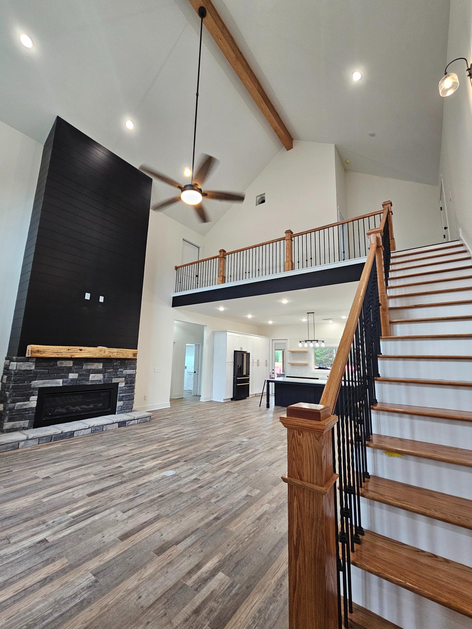 A room with a fireplace and a ceiling fan inside a Georgia barndominium